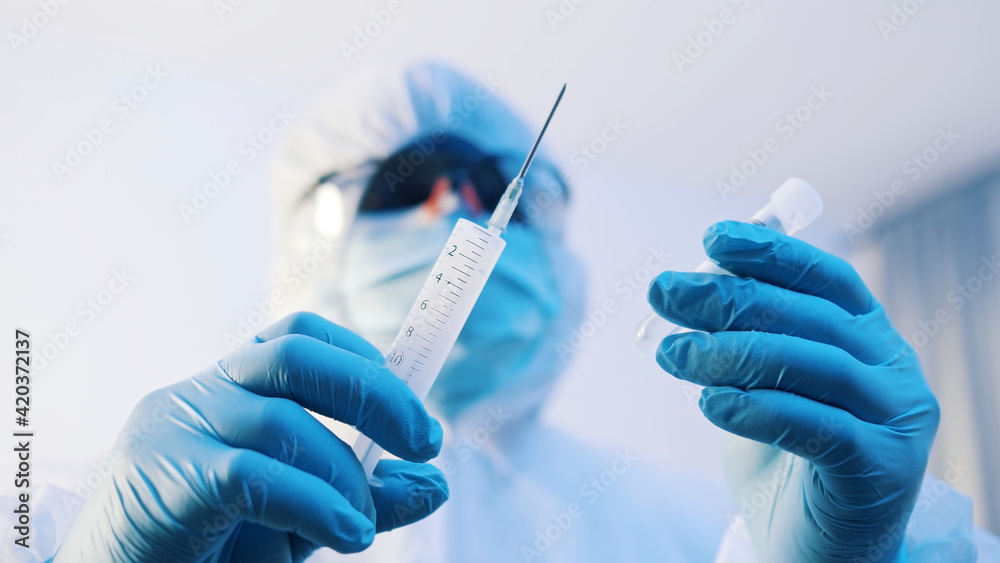 Vaccination and immunization against covid-19. Doctor in full uniform preparing vaccine. High quality photo Vaccination and immunization against covid-19. Doctor in full uniform preparing vaccine. High quality photo