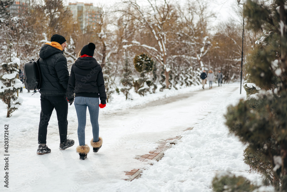 Young happy couple in love having a walk in a winter park Young happy couple in love having a walk in a winter park