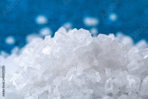 Coarse salt crystals on a blue table. sea salt. Background for advertising salty.