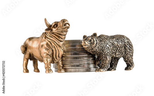 Isolated image of yellow metal bull and bear figurines against the background of a stack of coins. The concept of the symbol of stock trading, the struggle of buyers and sellers. A series of images. © mangz