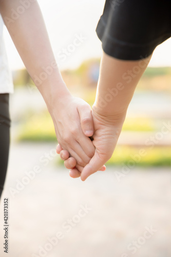 Senior mother walking hand in hand with daughter in urban park during summer time, concept of family love and care, mother day, family day, mom and daughter togetherness in pleasant urban summer