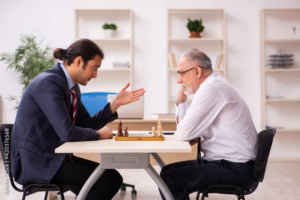 Two businessmen playing chess in the office Two businessmen playing chess in the office