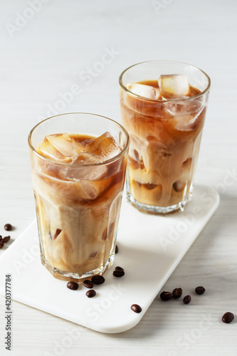 Iced coffee in a tall glass on white wooden table.