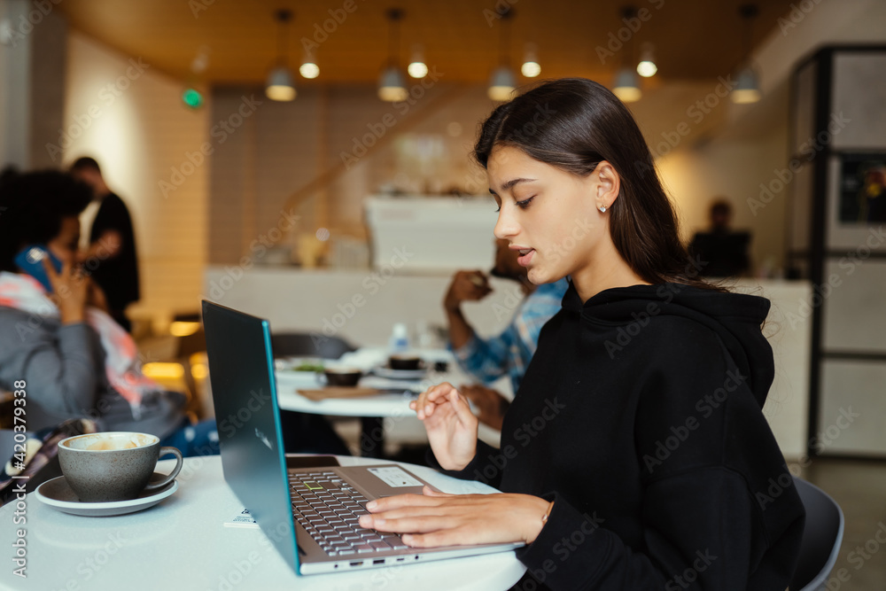 Portrait of female student using net-book while sitting in cafe Portrait of female student using net-book while sitting in cafe