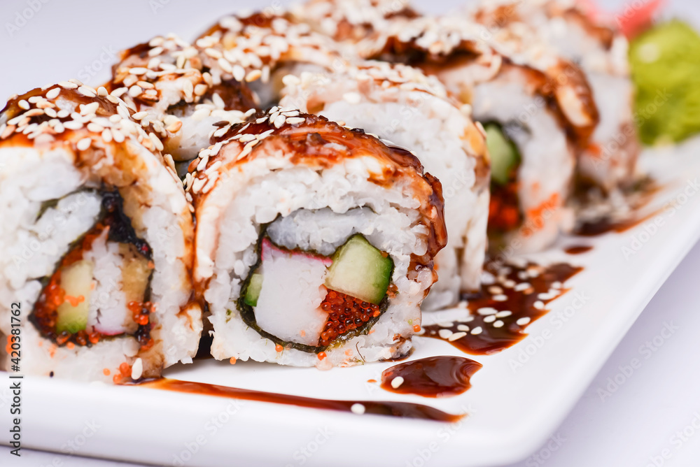 Eel, salmon and tuna sushi with unagi sauce served on a white plate over white background. Eel, salmon and tuna sushi with unagi sauce served on a white plate over white background.
