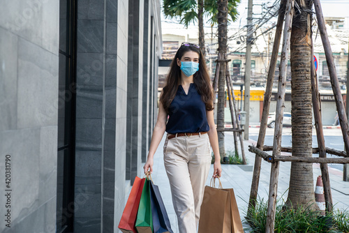 Beautiful woman wearing facemask  walk with shopping bags in city.