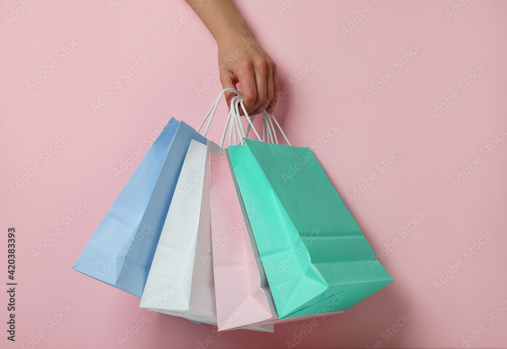 Female hand hold paper bags on pink background