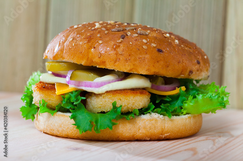 Delicious burger with chicken nuggets, cheese, pickled cucumber, fresh onion and lettuce..