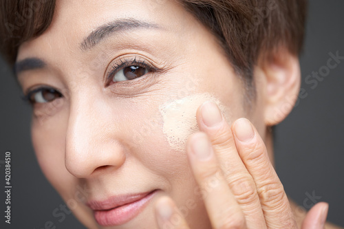 頬にファンデーションを塗る中年の日本人女性