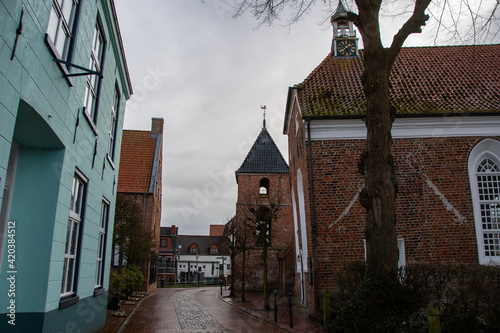 Fototapeta Naklejka Na Ścianę i Meble -  The view into the streets of the small port town of Greetsiel with the church