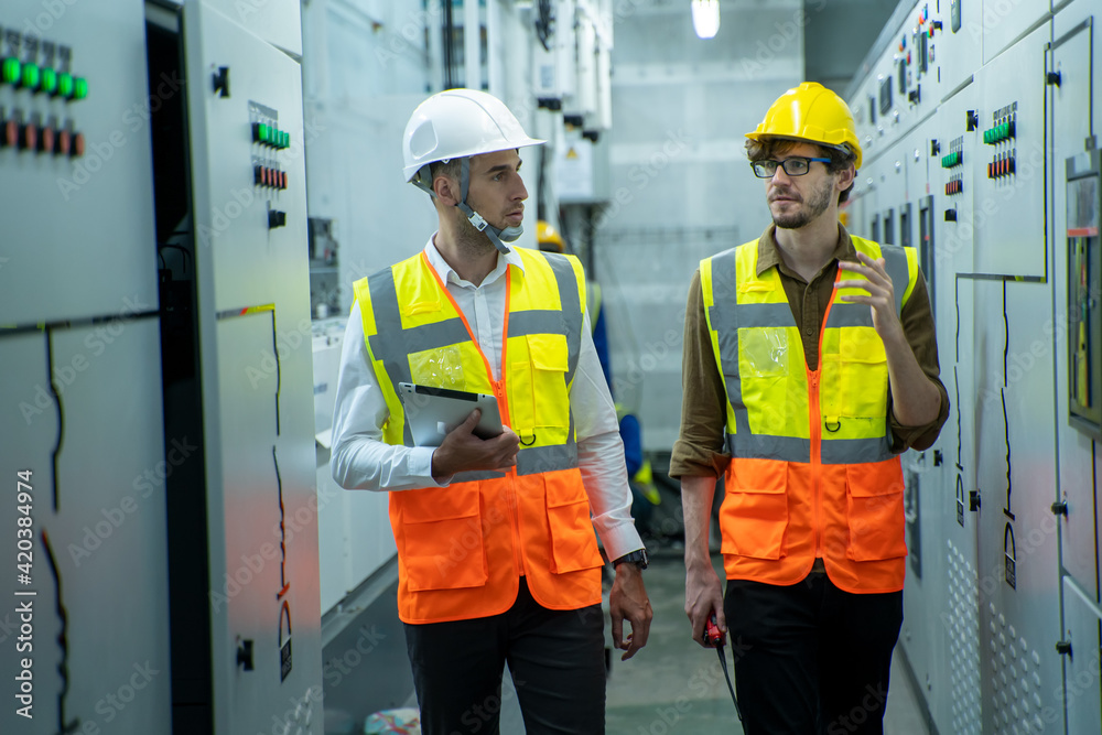 Maintenance engineers inspect relay protection system in control room of a modern thermal power plant at large industry factory. Maintenance engineers inspect relay protection system in control room of a modern thermal power plant at large industry factory.