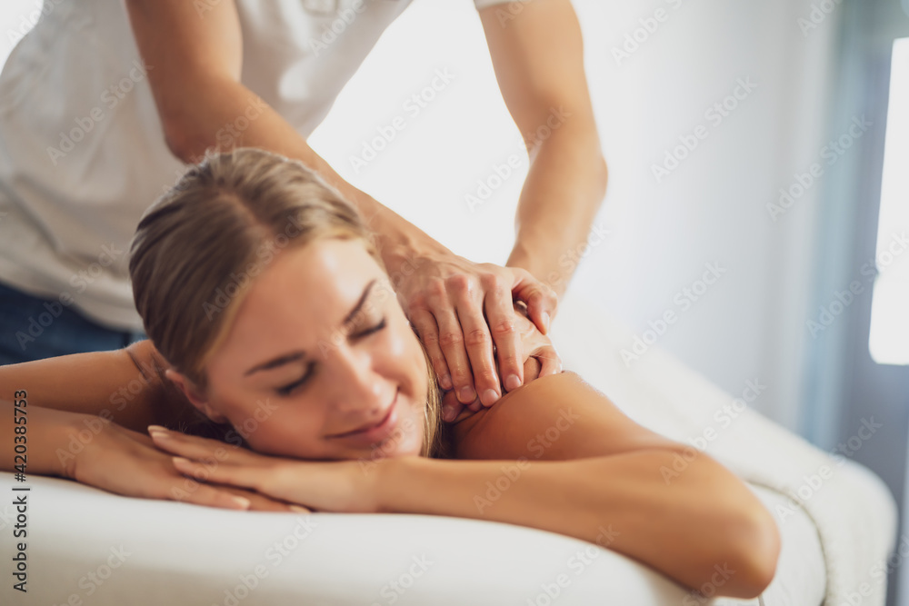 Professional masseur doing therapeutic massage. Woman enjoying massage in her home. Young woman getting relaxing body massage. Professional masseur doing therapeutic massage. Woman enjoying massage in her home. Young woman getting relaxing body massage.