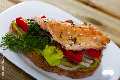Delicious sandwich with guacamole, baked trout fillet, sweet pepper, onion and greens..
