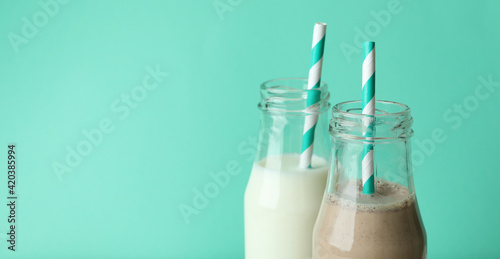 Bottles with milk and milkshake on mint background