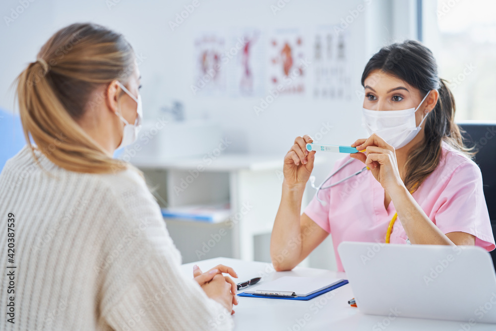 Doctor in mask explaining diagnosis to her female patient Doctor in mask explaining diagnosis to her female patient