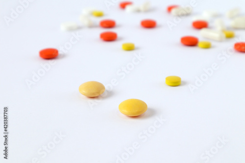 Yellow vitamins on the background of scattered ampoules and tablets on a light background, side view