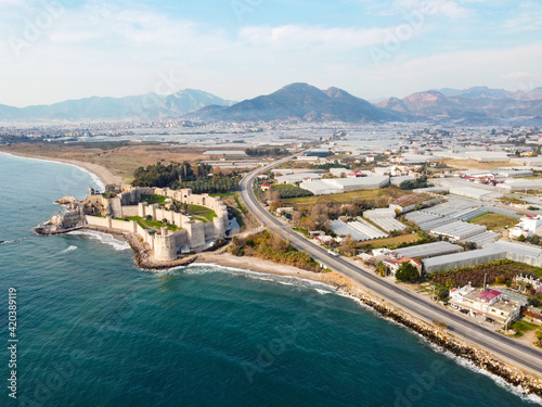 Mamure Castle or Mamure kalesi is a medieval castle in the Anamur district of Mersin Province, Turkey. Aerial view of castle, sea, mountains and numerous greenhouses