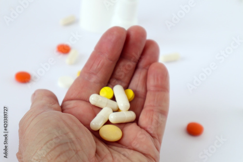 Colorful pills and ampoules in the hand of an elderly man, close-up