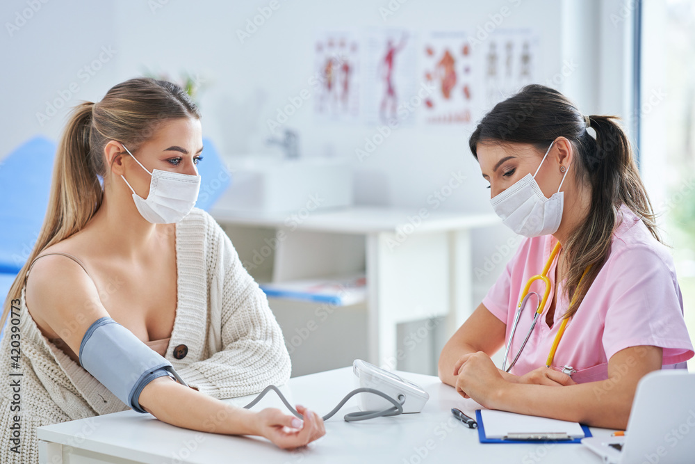 Doctor in mask explaining diagnosis to her female patient Doctor in mask explaining diagnosis to her female patient