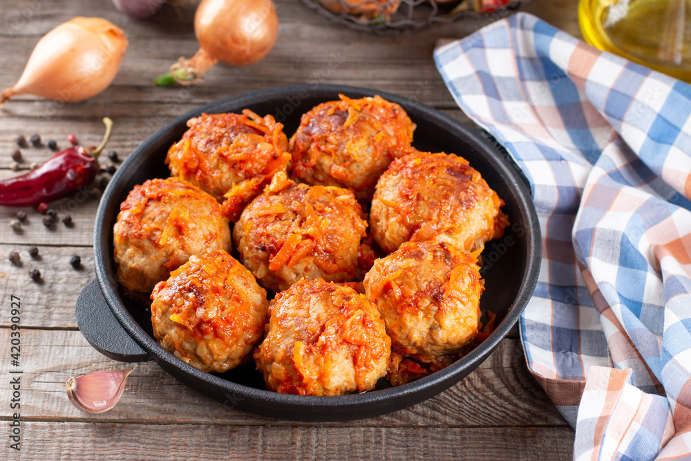 Meatballs from beef and pork with vegetables in a frying pan on a table Meatballs from beef and pork with vegetables in a frying pan on a table