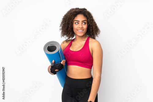 Fototapeta Naklejka Na Ścianę i Meble -  Young African American sport woman isolated on white background with a mat and smiling