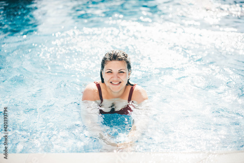 Happy plus size woman in swimming pool.