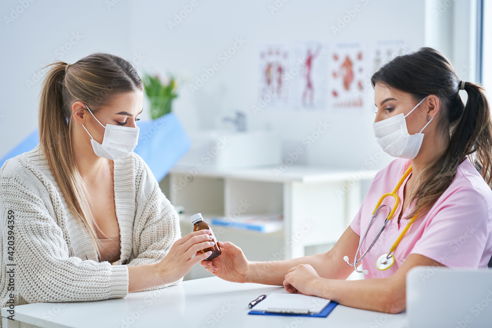 Doctor in mask explaining diagnosis to her female patient Doctor in mask explaining diagnosis to her female patient