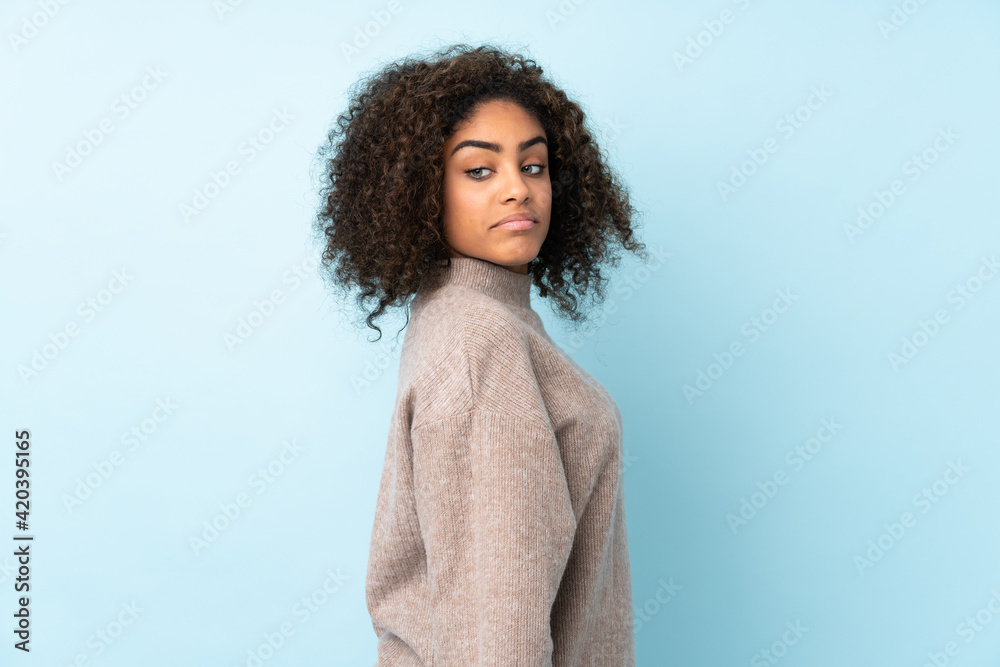 Young African American woman isolated on blue background . Portrait