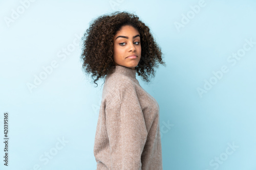 Young African American woman isolated on blue background . Portrait