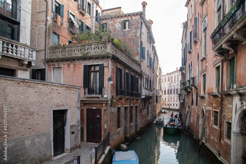 Venetian canal with old building facade in a sunny day, Italy
