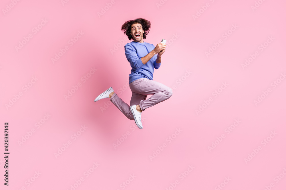 Full size photo of young happy shocked amazed crazy man jump fly browsing phone internet isolated on pink color background
