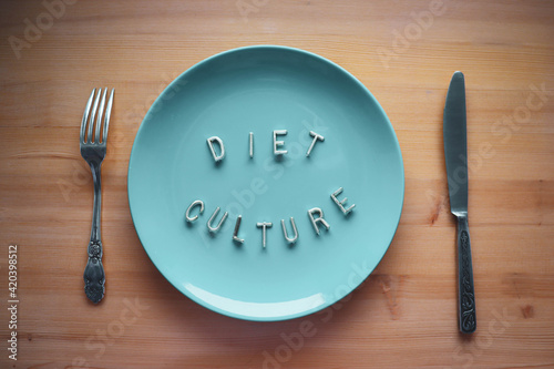 Fotografie A blue plate, a fork and a knife on a wooden table