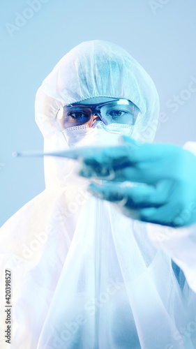 Female doctor in a protective suit holding a thermometer. High quality photo photo