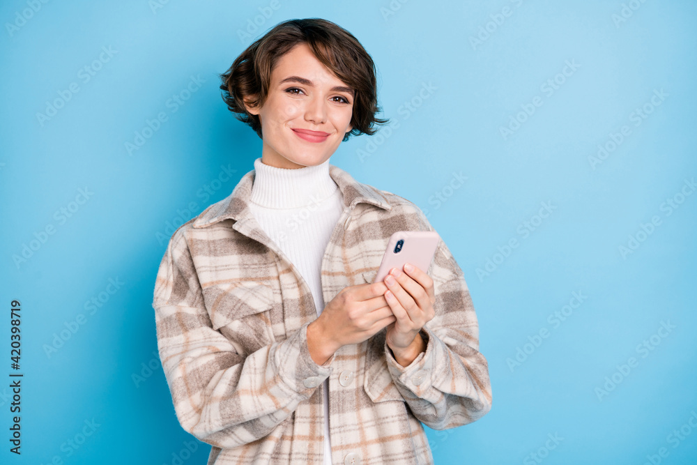 Photo of young attractive girl happy positive smile chat type sms cellphone isolated over blue color background Photo of young attractive girl happy positive smile chat type sms cellphone isolated over blue color background