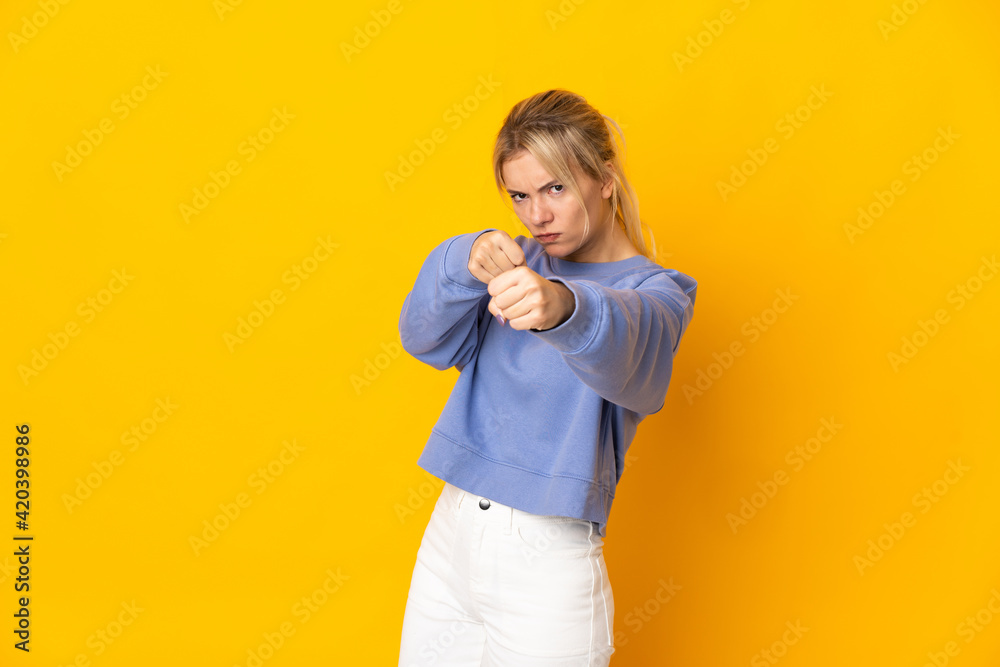 Young Russian woman isolated on yellow background with fighting gesture Young Russian woman isolated on yellow background with fighting gesture
