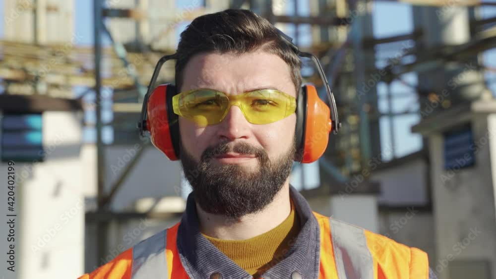 Portrait of smiling male worker wearing safety goggles and hearing protectors Portrait of smiling male worker wearing safety goggles and hearing protectors