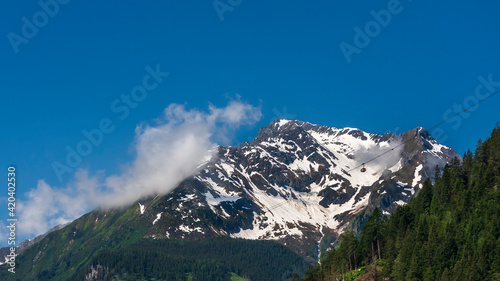 landscape with trees, snow, grass, roads, clouds and sky in Austria, Zillertal, in a sunny day