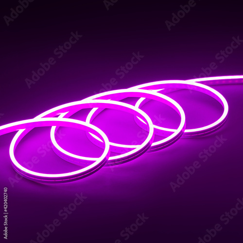 Flexible purple led tape neon glowing on black background