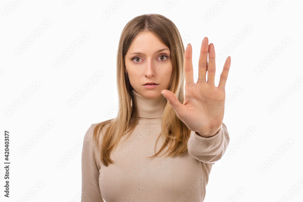 Serious blond girl keeps palm forward at camera, makes forbid sign, restricts or warns, extends arm in stop sign Serious blond girl keeps palm forward at camera, makes forbid sign, restricts or warns, extends arm in stop sign
