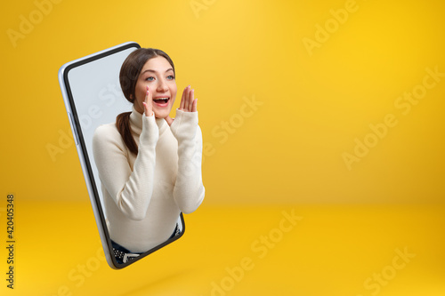 A beautiful girl got out of her smartphone and loudly shouts about the sale. Young woman browsing the Internet on a mobile phone screen with copy space.