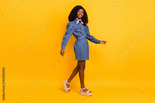 Full length profile portrait of charming dark skin lady look camera beaming smile isolated on yellow color background © deagreez