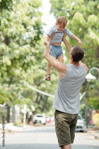 Young father having fun together with his son during his walk he raising his son up