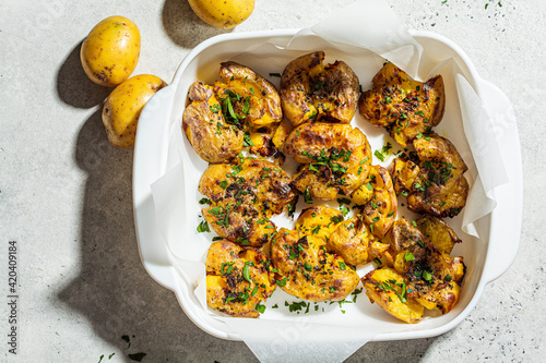 Εκτύπωση καμβά Baked smashed potatoes with herbs in white oven dish, top view.