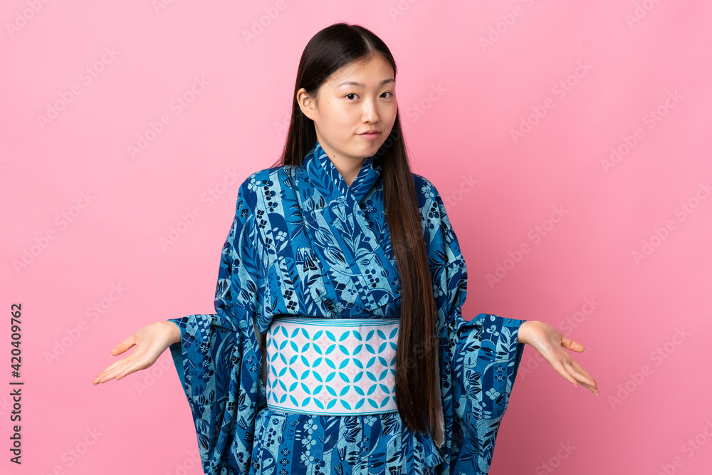 Young Chinese girl wearing kimono over isolated background having doubts Young Chinese girl wearing kimono over isolated background having doubts