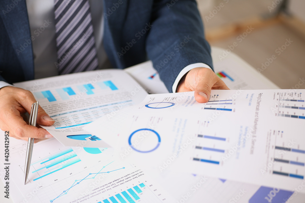 Male hands hold documents with financial statistics Male hands hold documents with financial statistics