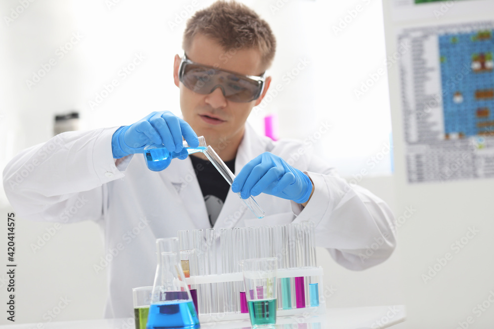 A male chemist holds test tube of glass in his hand overflows a liquid solution A male chemist holds test tube of glass in his hand overflows a liquid solution