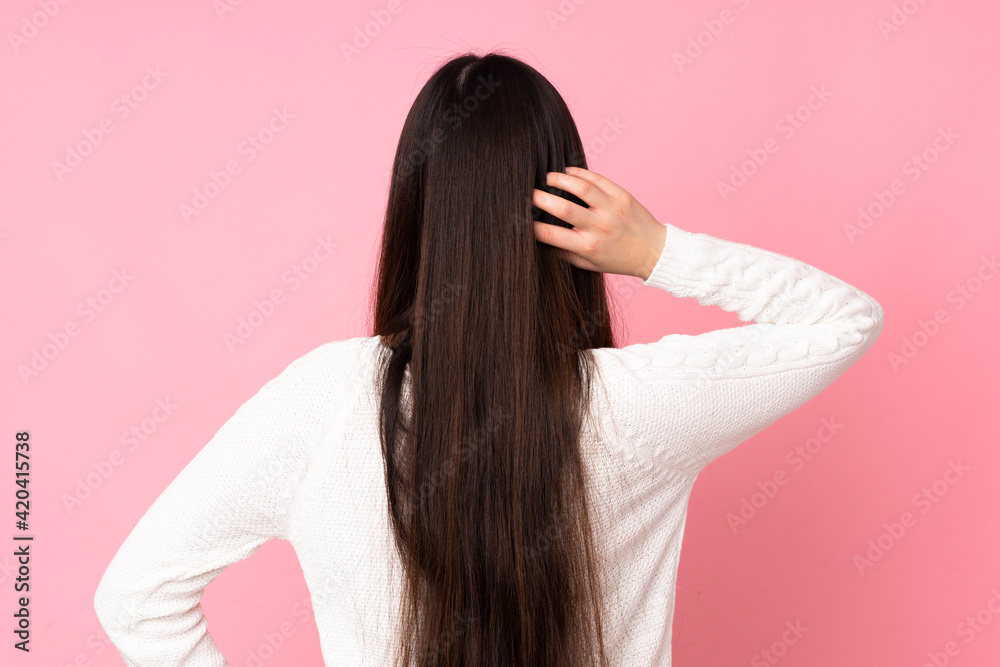 Young asian woman over isolated background in back position and thinking Young asian woman over isolated background in back position and thinking