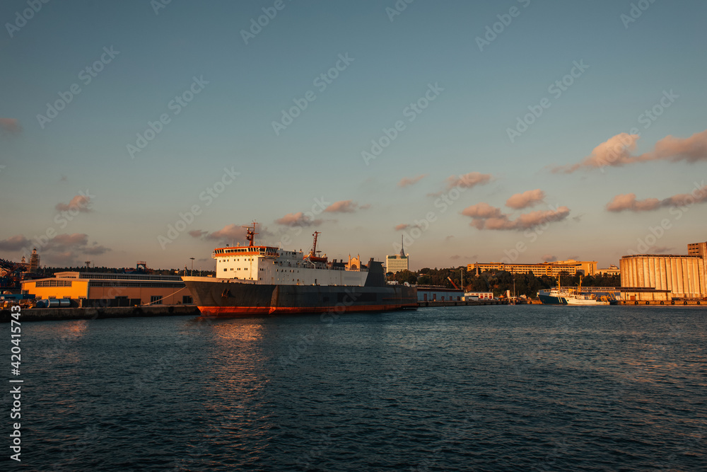 Cargo ship in sea and buildings on coast of Istanbul during sunset, Turkey