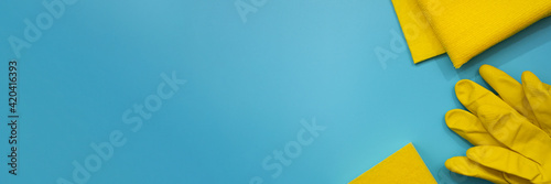 Obraz na płótnie Yellow protective gloves, sponge and cloths on blue background. Top view of cleaning supplies. Banner. Copy space. Spring house cleaning concept. w salonie