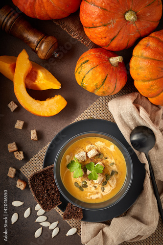 Pumpkin cream soup. Bowl with soup  and orange pumpkins on gray background. Top view. Healthy, vegetarian food. Lenten menu